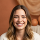 A candid portrait of a smiling young woman with warm eyes, exuding happiness and trust.